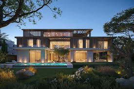 Modern two-story house with large windows, illuminated warmly at dusk. A glowing swimming pool is in front, surrounded by neatly landscaped greenery—perfect for those seeking premium Dubai real estate.